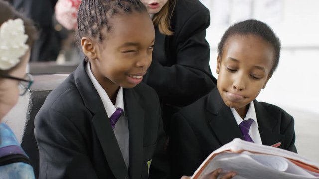  Young girls in school looking at exercise book & talking