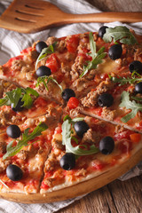 Hot pizza with tuna, olives and arugula close-up. vertical
