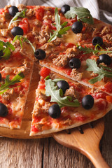 Sliced pizza with tuna, olives and arugula close-up. vertical
