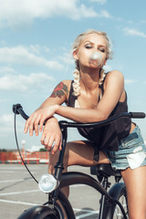 Obraz premium Pretty blonde woman with bicycle in city