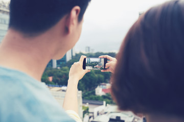 Couple taking photo of city on smartphone