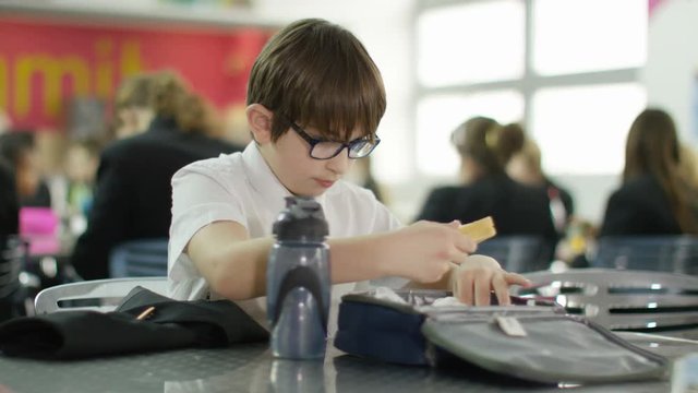  Sad boy eating lunch alone in school cafeteria