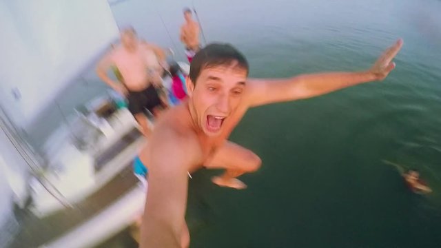 Group of young friends jumping into sea from the sail boat in slowmotion. 1920x1080