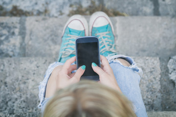 Girl texting while sitting on the stairs outdoors.