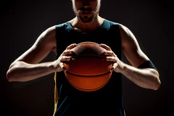 Poster Silhouette view of a basketball player holding basket ball on black background © master1305