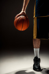 Silhouette view of a basketball player holding basket ball on black background