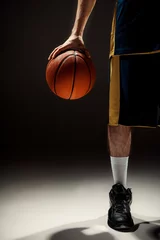 Poster Silhouette view of a basketball player holding basket ball on black background © master1305