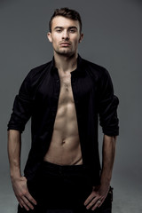 Naklejka premium sexy young fashion man wearing a black shirt unbuttoned