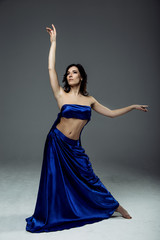 Beautiful young woman dancer in blue top, long blue skirt dancing.  