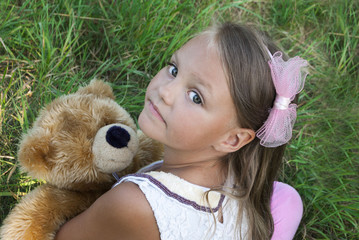 cute little girl in grass with teddy bear