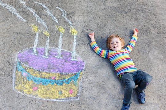 Kid boy having fun with colorful birthday cake drawing with chal