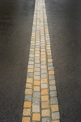 Gepflasterte Entwässerungsrinne aus Naturstein in asphaltierter Straße - Paved gutter made ​​of natural stone in a road made of asphalt