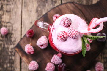 Pink raspberry smoothie with ice cream and mint on a rustic wood background