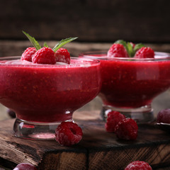 Pink raspberry smoothie with ice cream and mint on a rustic wood background