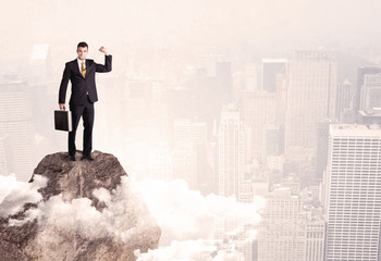 Happy businessman standing on stone top