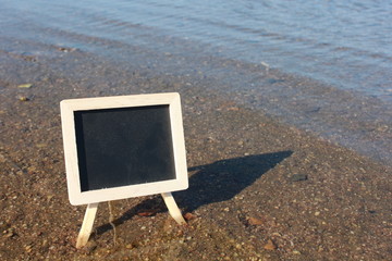 Blank blackboard standing in water