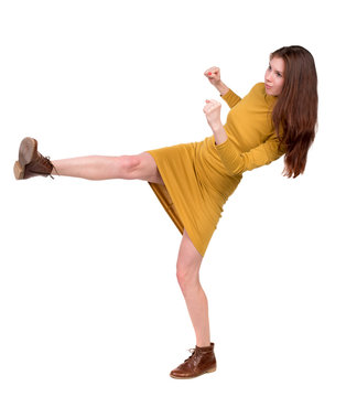 skinny woman funny fights waving his arms and legs. Isolated over white background. Long-haired brunette in a mustard-colored falls.