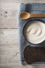 Sour cream on the ceramic dish with bread on the white wooden table vertical