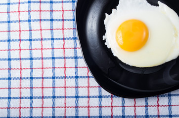 Top view on a black plate with a fried egg