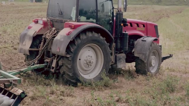 An agricultural tractor, plowing a field for sowing, turning right.