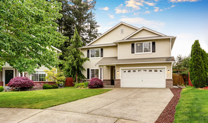 American house with siding trim and well kept garden around.