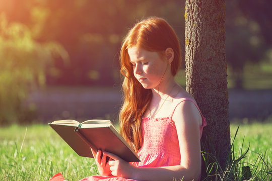 Little Redhead Girl Reading Book At Nature