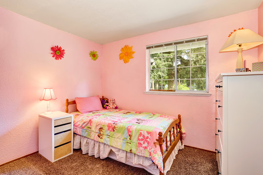 Pink kids bedroom with white furniture and carpet floor.