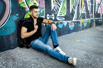 cool trendy stylish sexy handsome hipster guy on the graffiti background in the city