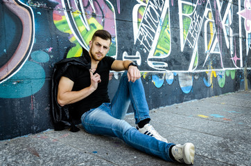 cool trendy stylish sexy handsome hipster guy on the graffiti background in the city © smmartynenko