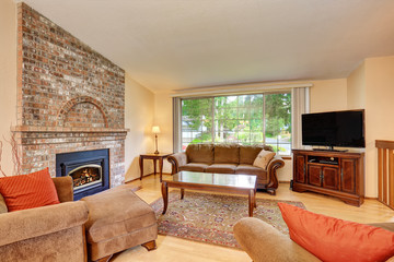 Cozy living room interior with tv set, brick fireplace and rug.