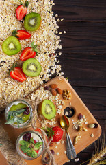 Wooden desk with two jar of granola with kiwi and strawberry . wooden background .closeup