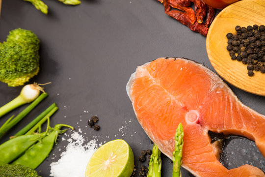 Flat lay of raw salmon fillet and ingredients for cooking on a d