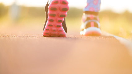 Runner feet running on road closeup on shoe. woman fitness sunri