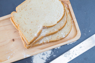 Sliced whole wheat bread on wood plate black background