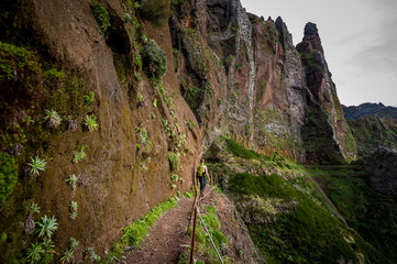 Fototapeta na wymiar Woman hiker is going on the edge of steep mountain
