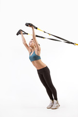 Upper body excercise concept on TRX. Beautiful young woman training with suspension trainer sling...