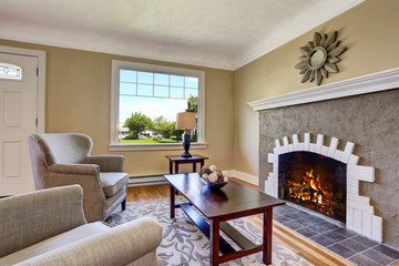 Living room with brick fireplace, deep brown furniture and rug.