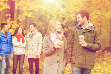 group of smiling friend with coffee cups in park