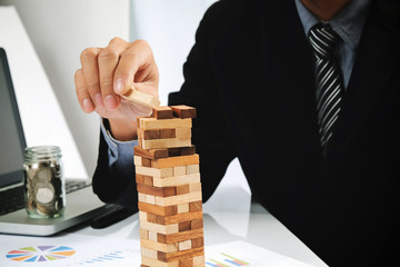 business man placing wooden block on a tower concept risk contro