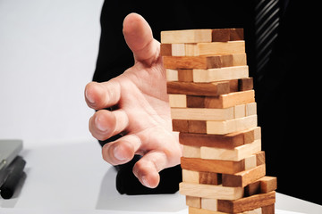business man placing wooden block on a tower concept risk contro