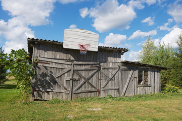 Old wooden barn with a basketball hoop attached.