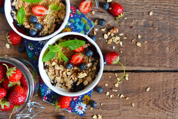 Berry crumble with oatmeal and almonds on wooden background