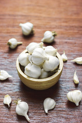 White garlic in the wooden bowl on wood floor