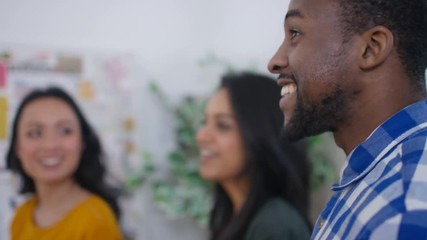  Workers in creative office, looking at noticeboard & discussing ideas