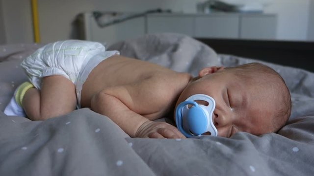 Newborn sleepy baby sucks pacifier