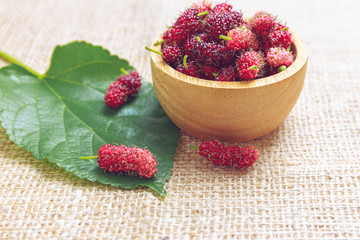 Red mulberry in wooden bowl and on cloth floor