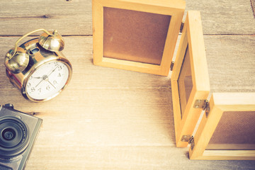 Camera, clock and frame of photography on the wood floor