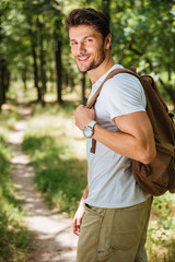 Man holding backpack and walking in forest