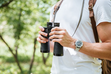 Man with backpack and binoculars in forest