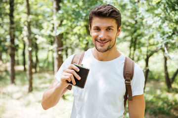 Man with backpack and flask walking in forest